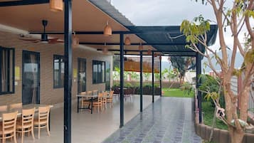 Un espace extérieur aménagé en patio, avec un coin salon abrité, une table à manger et des chaises.