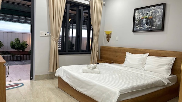 A hotel room with a bed, curtains, a painting, and a view of the outside.