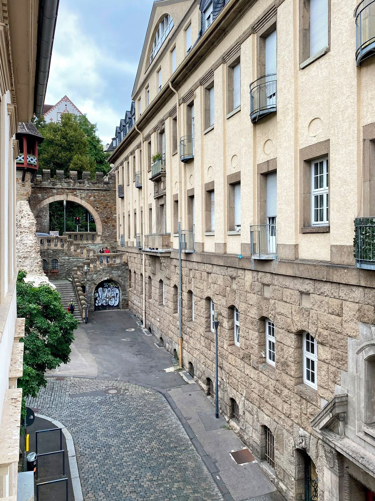 Una estrecha calle adoquinada bordeada por edificios históricos de piedra con ventanas y balcones de arco.