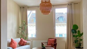 A living room with a sofa, a round coffee table, a chair, a hanging light fixture, and a potted plant. - Charming Old Town Apartment in Wiesbaden, 2 Bedrooms, Parking Garage 150 m Away (Wiesbaden)