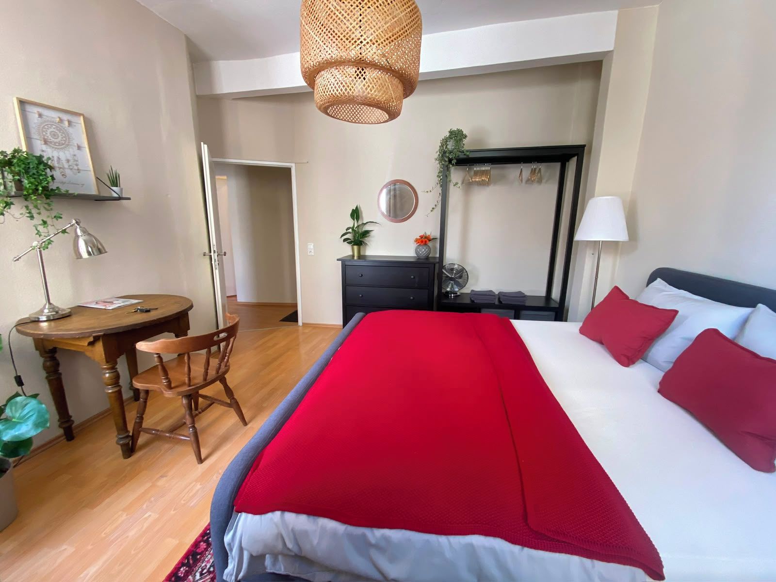 Ein Hotelzimmer mit einem Bett, einem Schreibtisch, einem Stuhl, einer Kommode, einem Spiegel und einer Deckenleuchte.
