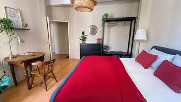Ein Hotelzimmer mit einem Bett, einem Schreibtisch, einem Stuhl, einer Kommode, einem Spiegel und einer Deckenleuchte.