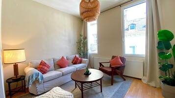 Ein Wohnzimmer mit Sofa, Sessel, Couchtisch, Lampe und einer Pendelleuchte.