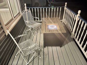 A wooden deck with two white metal chairs and a small table with a decorative light. - Agate Bay Getaway - Short Walk to Lake Superior & Downtown (Two Harbors)