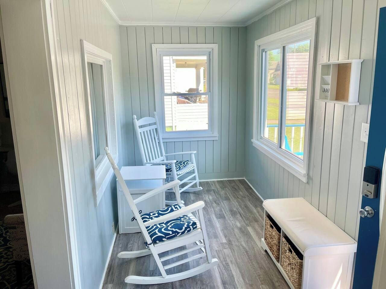 A room with a bench, rocking chairs, and a window.