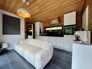 A modern kitchen with a built-in espresso machine, a sofa, and a large window. - Naturblick Oasis - Waren (Müritz) (Waren (Müritz))