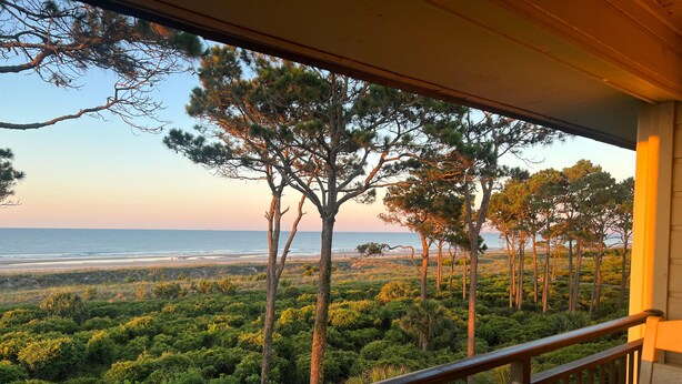 Ein Balkon mit Blick auf das Meer und einen bewaldeten Bereich.