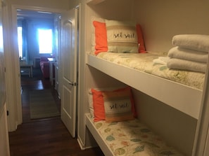 Een kamer met stapelbedden, elk voorzien van een kussen met de tekst 'set sail', en een stapel witte handdoeken.