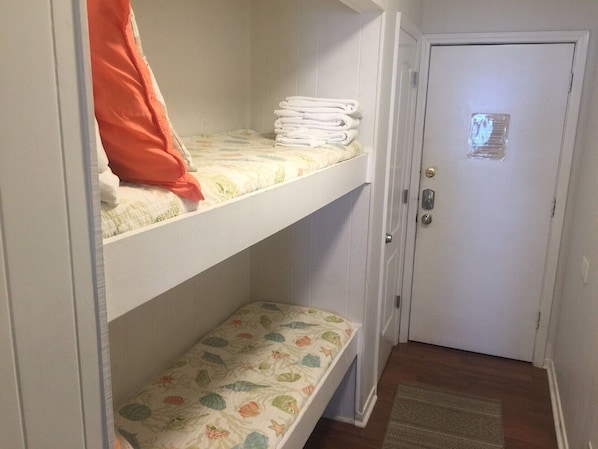 A room with a bunk bed, a door with a security lock, and a patterned rug on the floor.