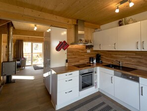 Una cocina moderna con gabinetes blancos, horno empotrado y cafetera.