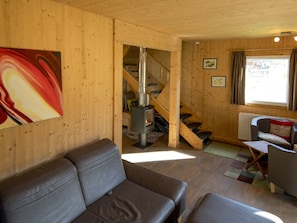 Un interior de madera con un sofá, una escalera, un radiador y una ventana.