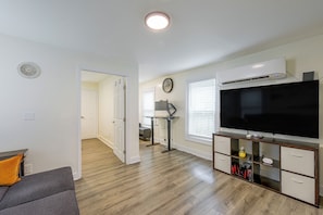 A modern living room with hardwood flooring, a flat-screen TV, a coffee table, and a sofa.