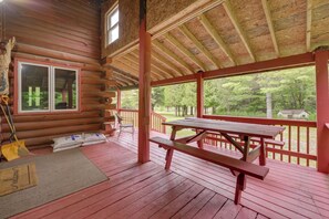 A wooden cabin with a covered porch, a picnic table, and a view of the surrounding forest. - Rustic Family Getaway w/ Pond in Prattsburgh (Prattsburgh)