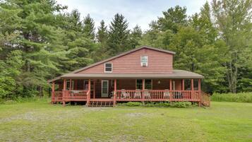 A two-story log cabin with a porch and outdoor seating area.