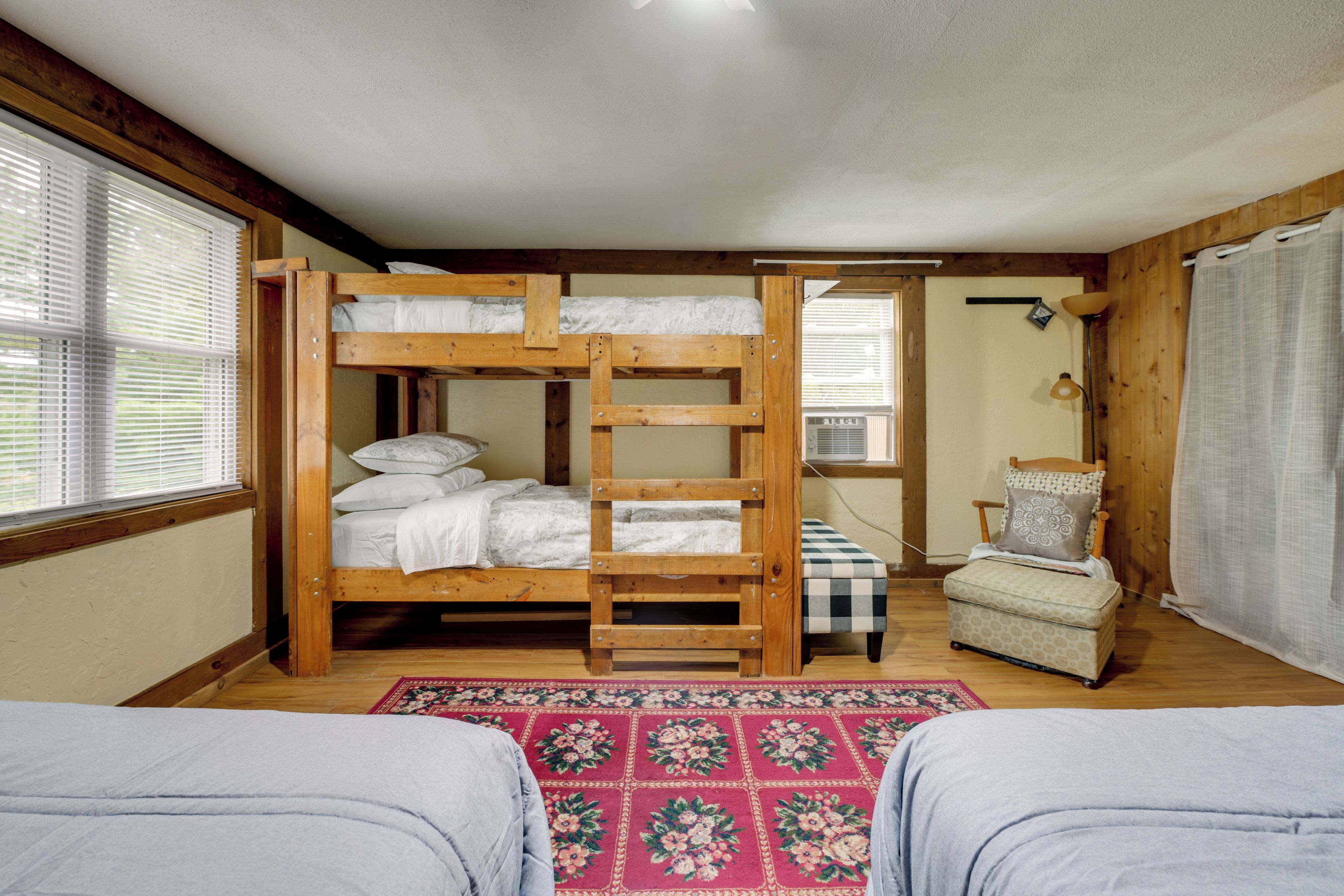 A bunk bed room with a wooden ladder, a chair, and a small table.