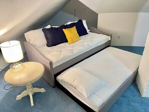 Quarto compacto com cama, mesinha e abajur.