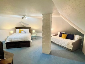 Ein Schlafzimmer mit einem Bett, einem Schlafsofa, einem Nachttisch und einer Lampe.