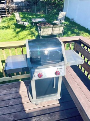 Ein Grill mit zwei Drehreglern, einem digitalen Display und einer seitlichen Ablagefläche auf einer Holzterrasse.