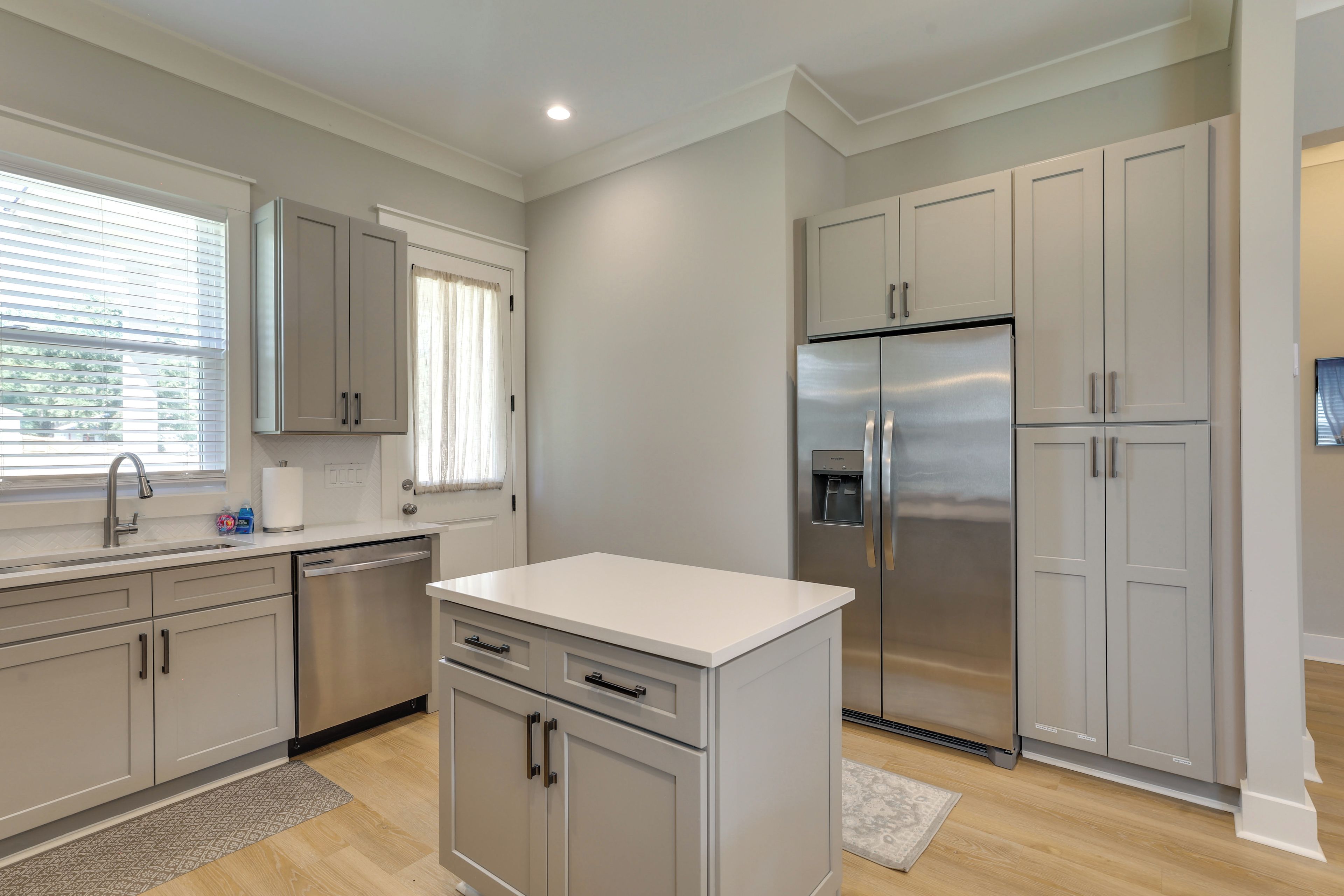 A modern kitchen with stainless steel appliances, light-colored cabinetry, and a window providing natural light.