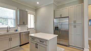 A modern kitchen with stainless steel appliances, light-colored cabinetry, and a window providing natural light.