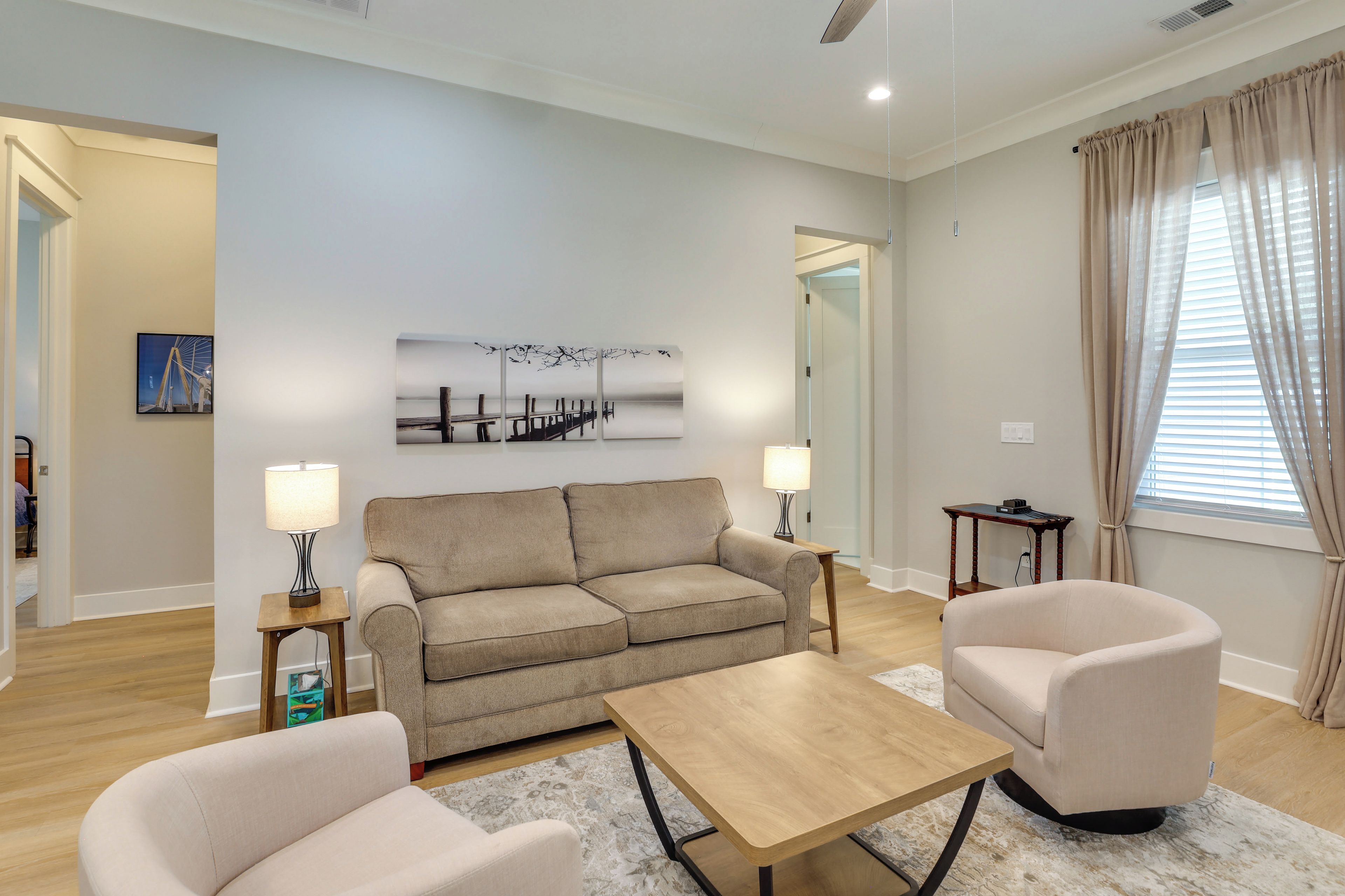 A modern living room with a sofa, two armchairs, a coffee table, and a painting on the wall.