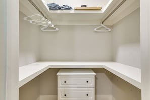 Ein Schrank mit weißen Einlegeböden, zwei Schubladen und einem Oberlicht darüber.