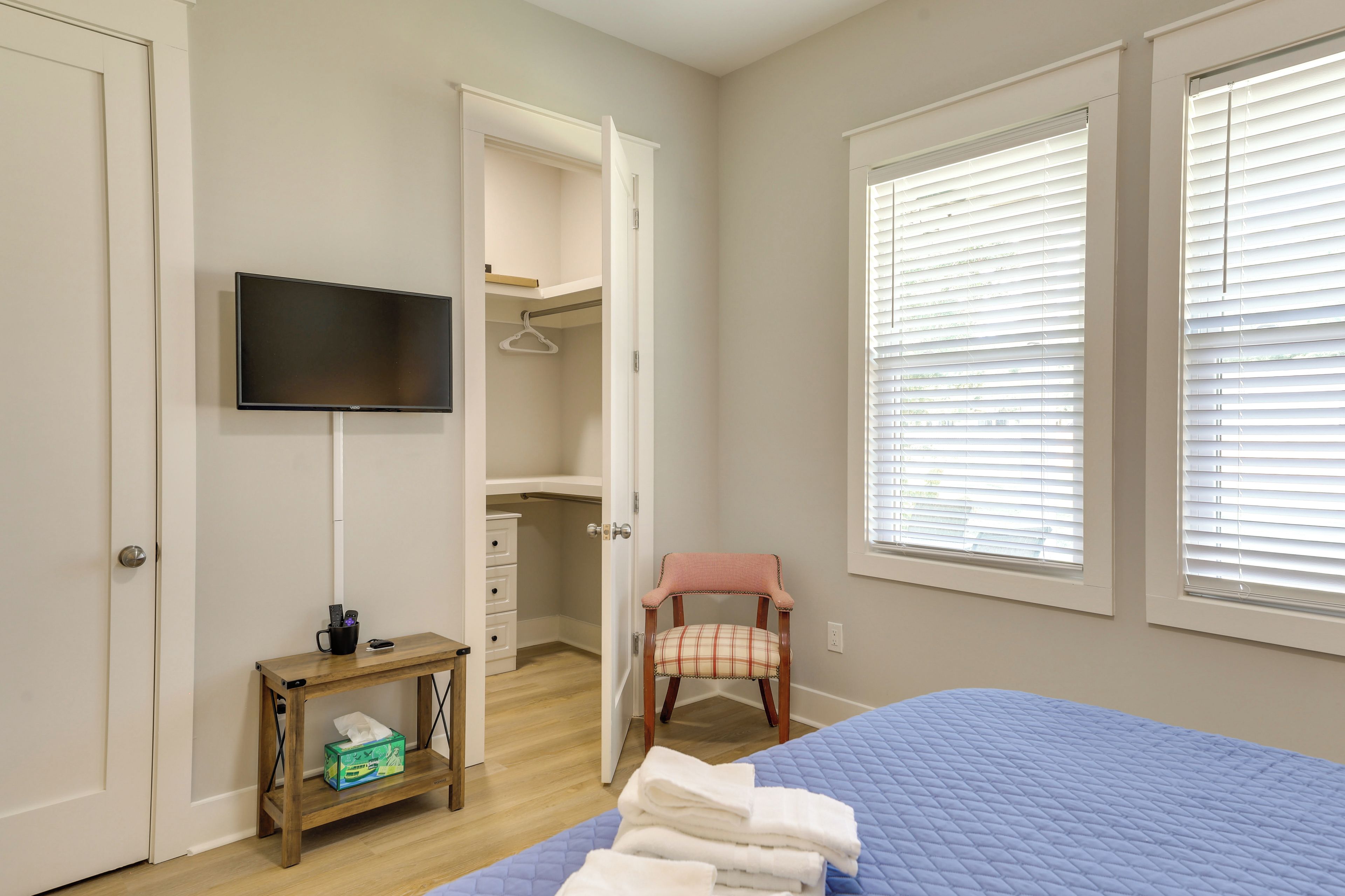 A bedroom with a bed, a television, a chair, a small table, and a closet.