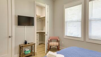 A bedroom with a bed, a television, a chair, a small table, and a closet.