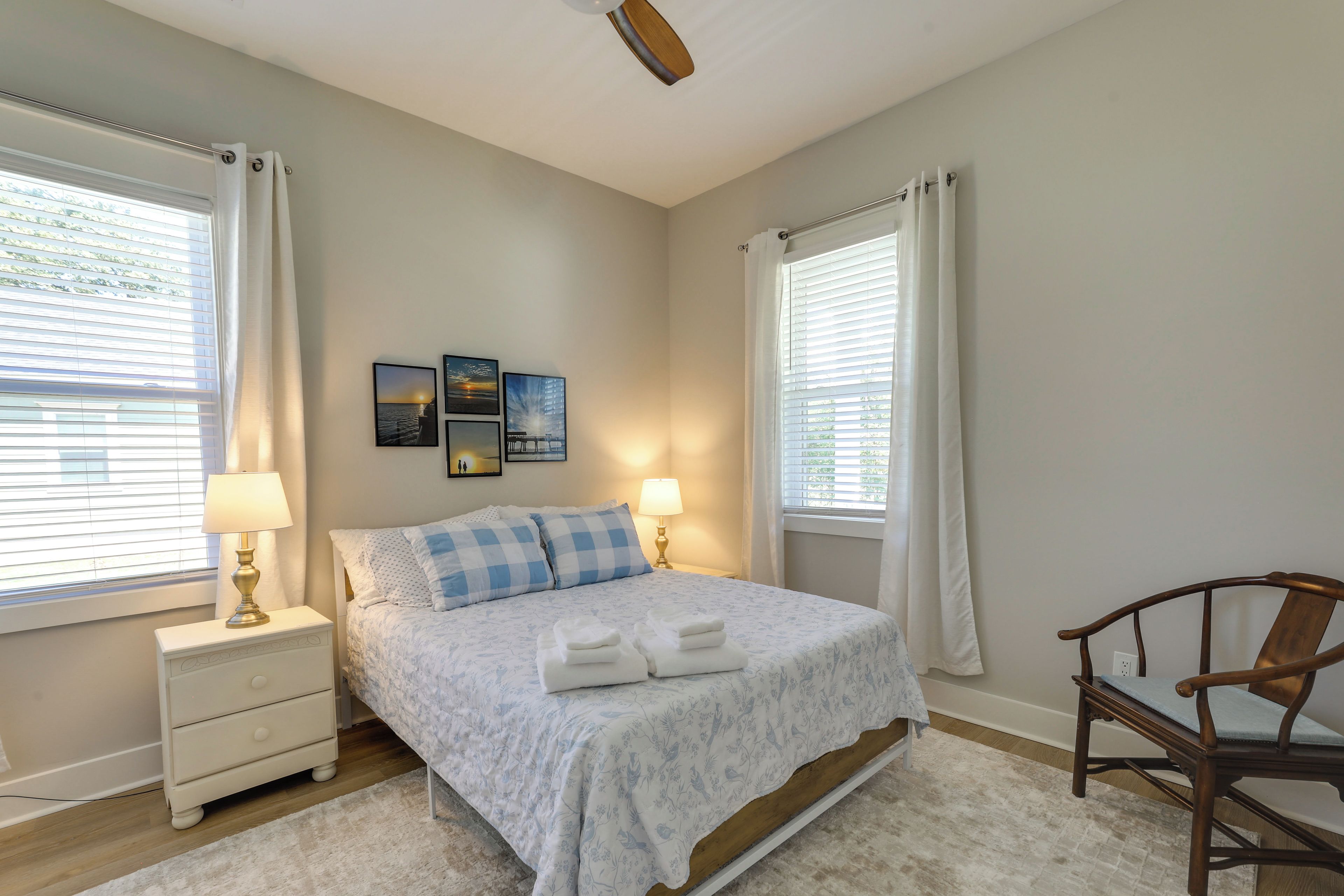 A bedroom with a bed, two bedside tables, a chair, and a window with curtains.