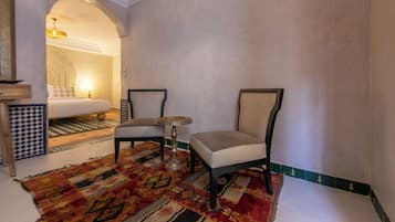 A hotel room with a bed, two chairs, a small table, and a patterned rug.
