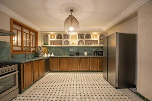 Una cocina con armarios de madera, un refrigerador de acero inoxidable y un piso con diseño.