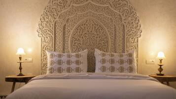 A bed with a decorative headboard, two bedside lamps, and matching pillows.