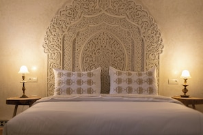 A bed with a decorative headboard, two bedside lamps, and matching pillows.