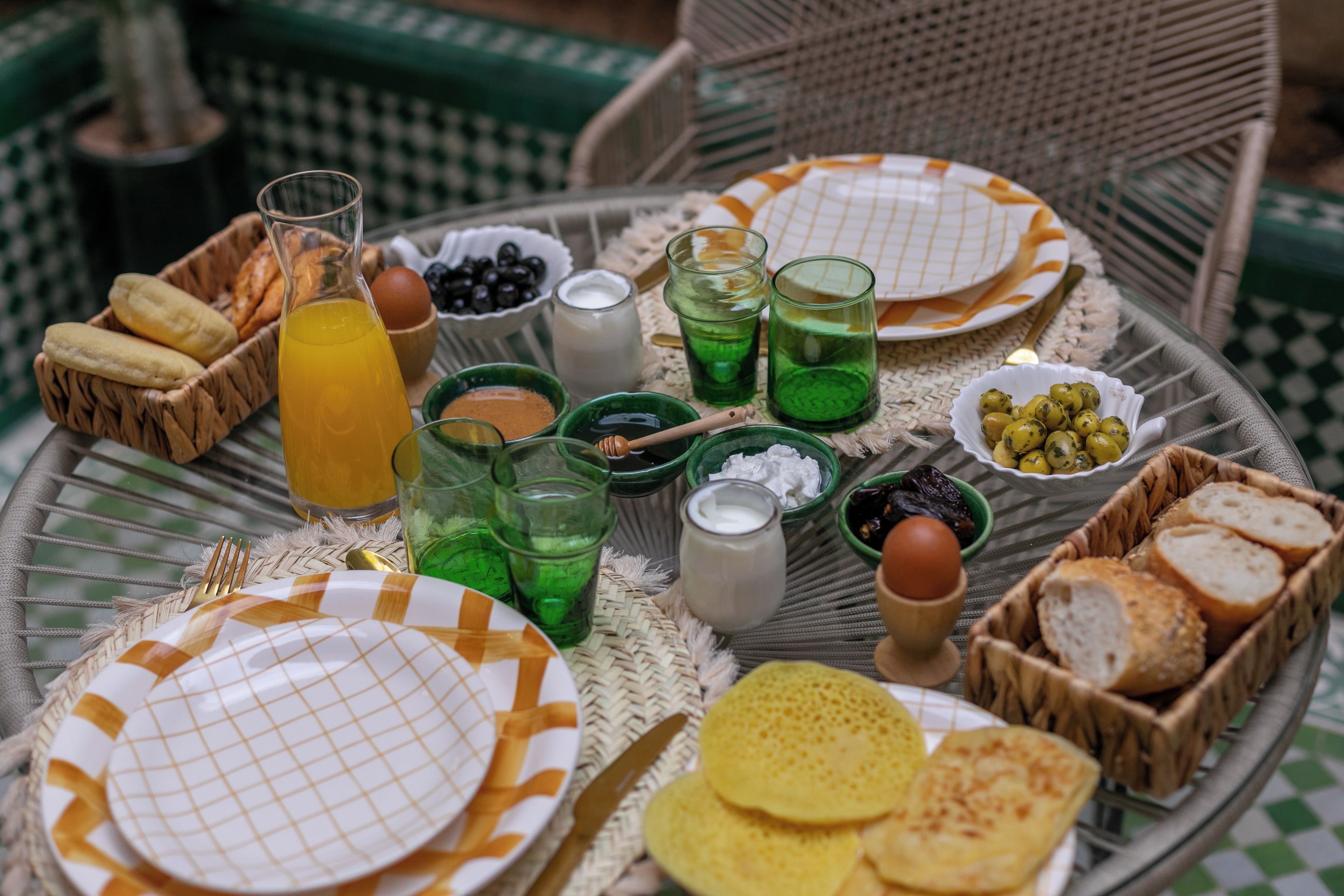 Een ronde tafel met diverse ontbijtartikelen zoals brood, eieren en drankjes.