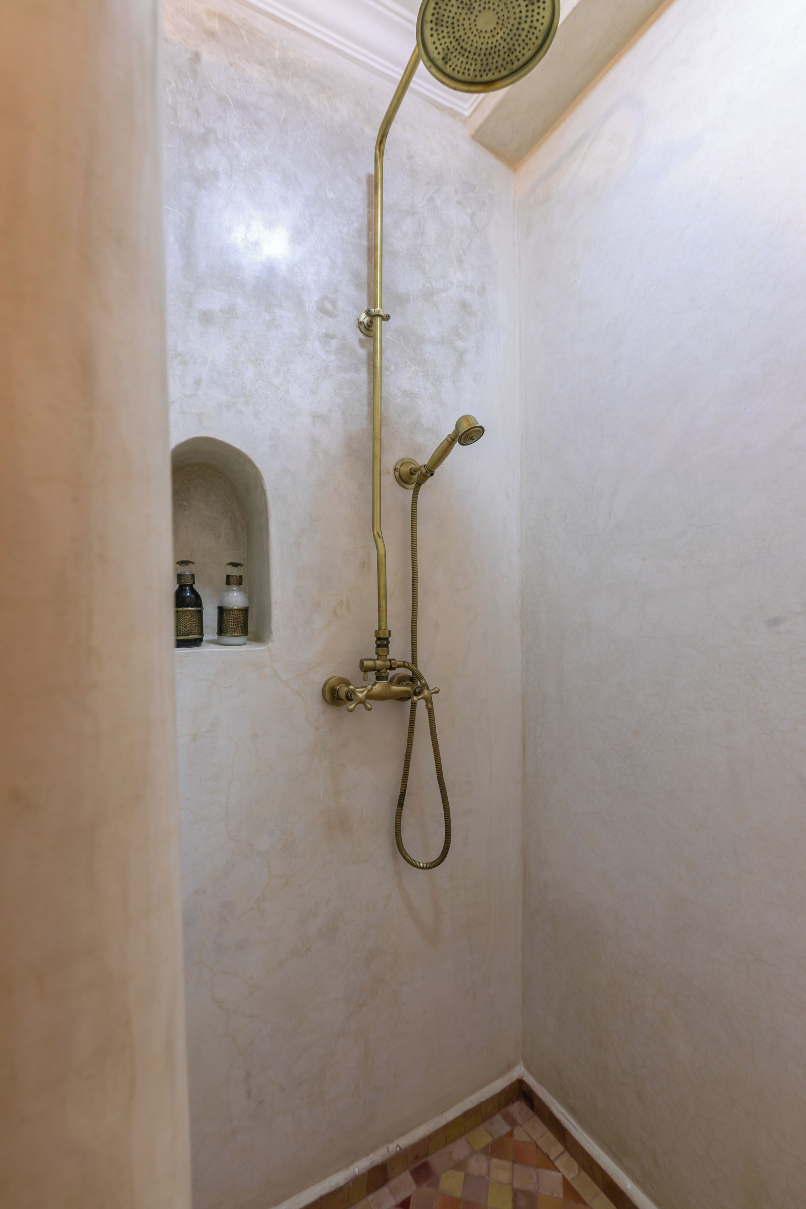 A shower with a handheld showerhead and a wall-mounted faucet.
