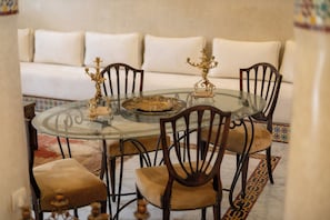 A round glass table with ornate metal candelabras, surrounded by wooden chairs with cushioned seats. - Riad Dar Razallah  (Marrakech)