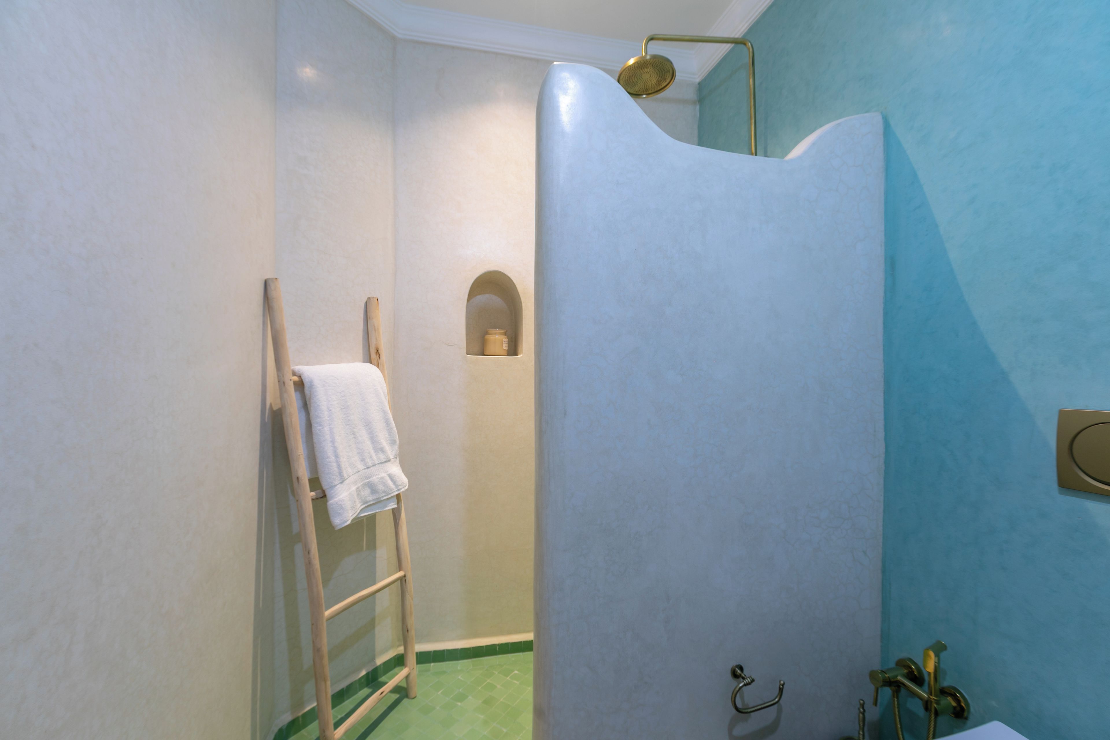 Ein Badezimmer mit einer Dusche, einem Handtuchhalter und einer kleinen Ablagefläche.