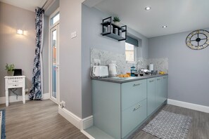 A modern kitchen with a light blue cabinet, a white countertop, and a wall-mounted clock. - Sea Folly Luxury Townhouse, Central, Parking, Seafront 400m (Sidmouth)