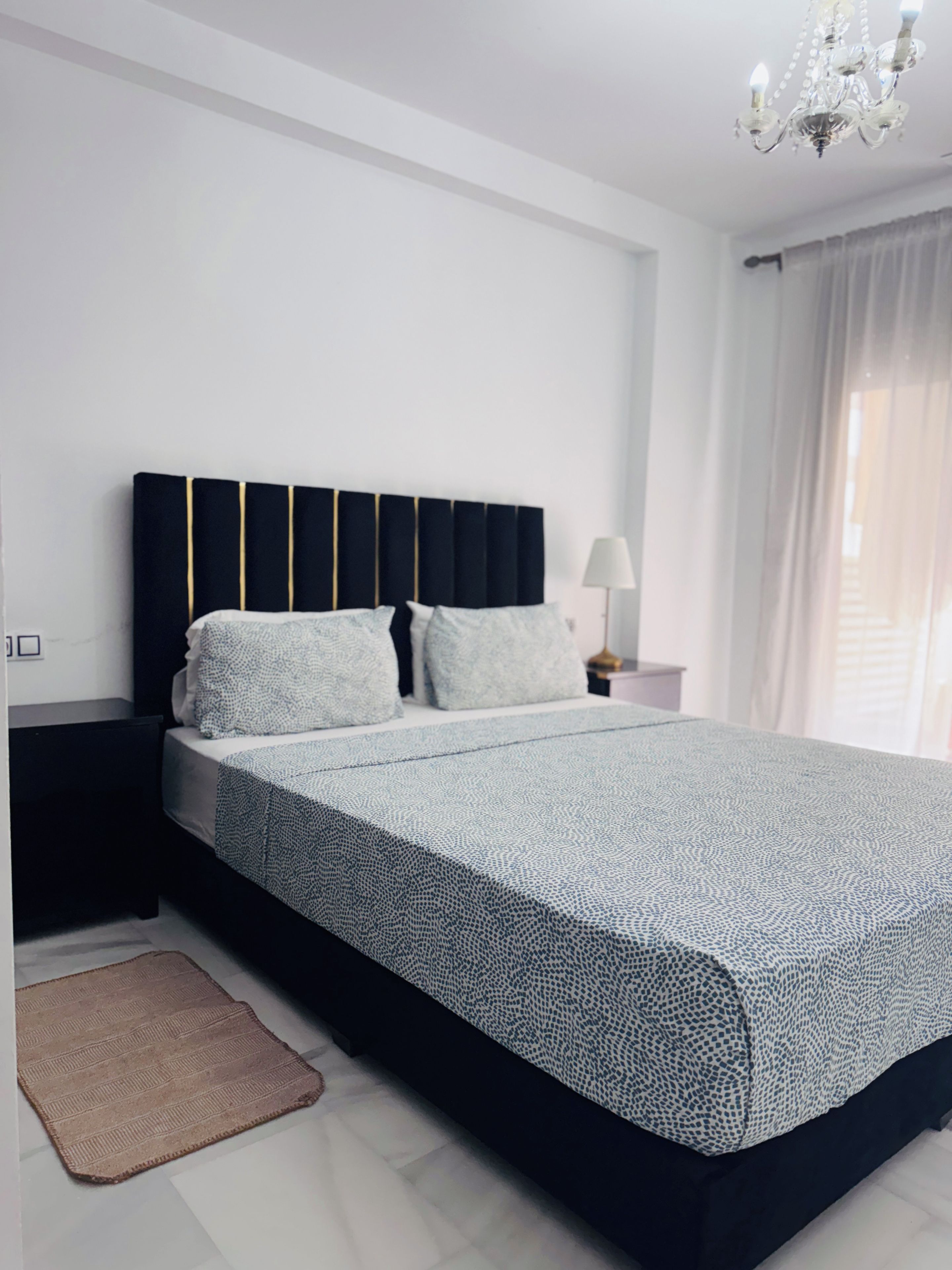 Un dormitorio moderno con una cama grande, una mesita de noche, una lámpara y una araña.