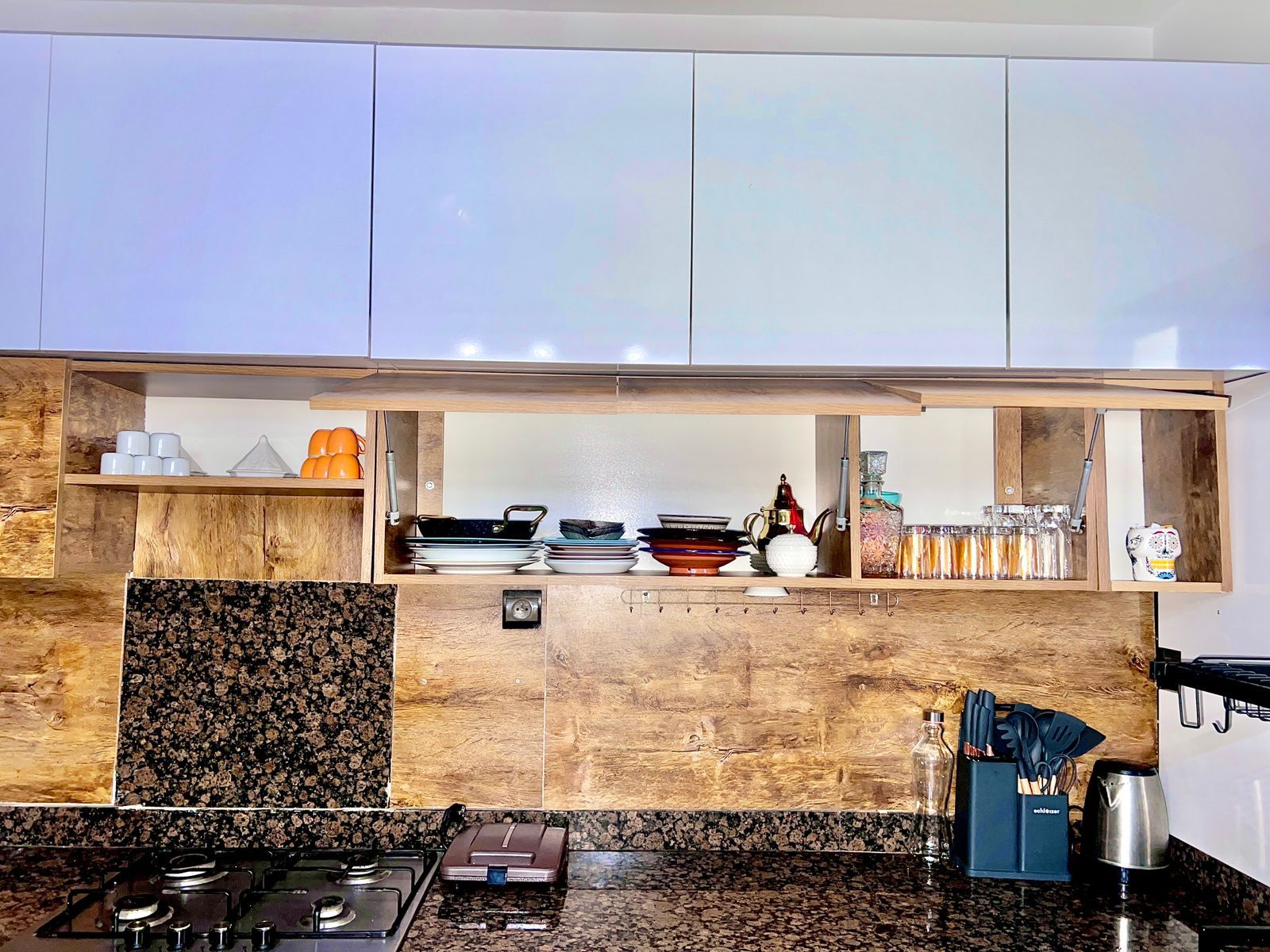 A modern kitchen with a gas stove, wooden cabinets, and a granite countertop.