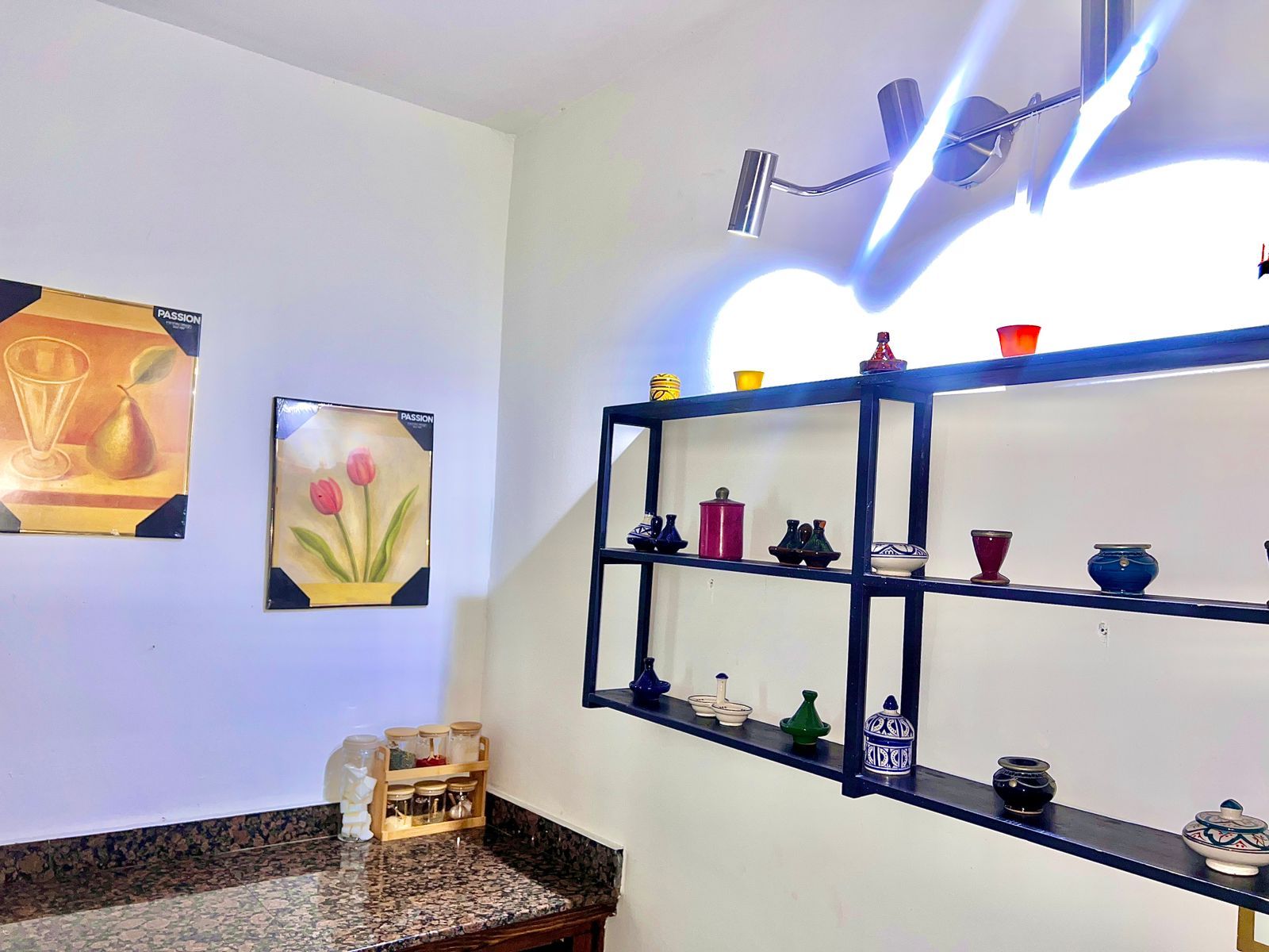 Una cocina con encimera de granito, un estante negro con adornos y una obra de arte en la pared.