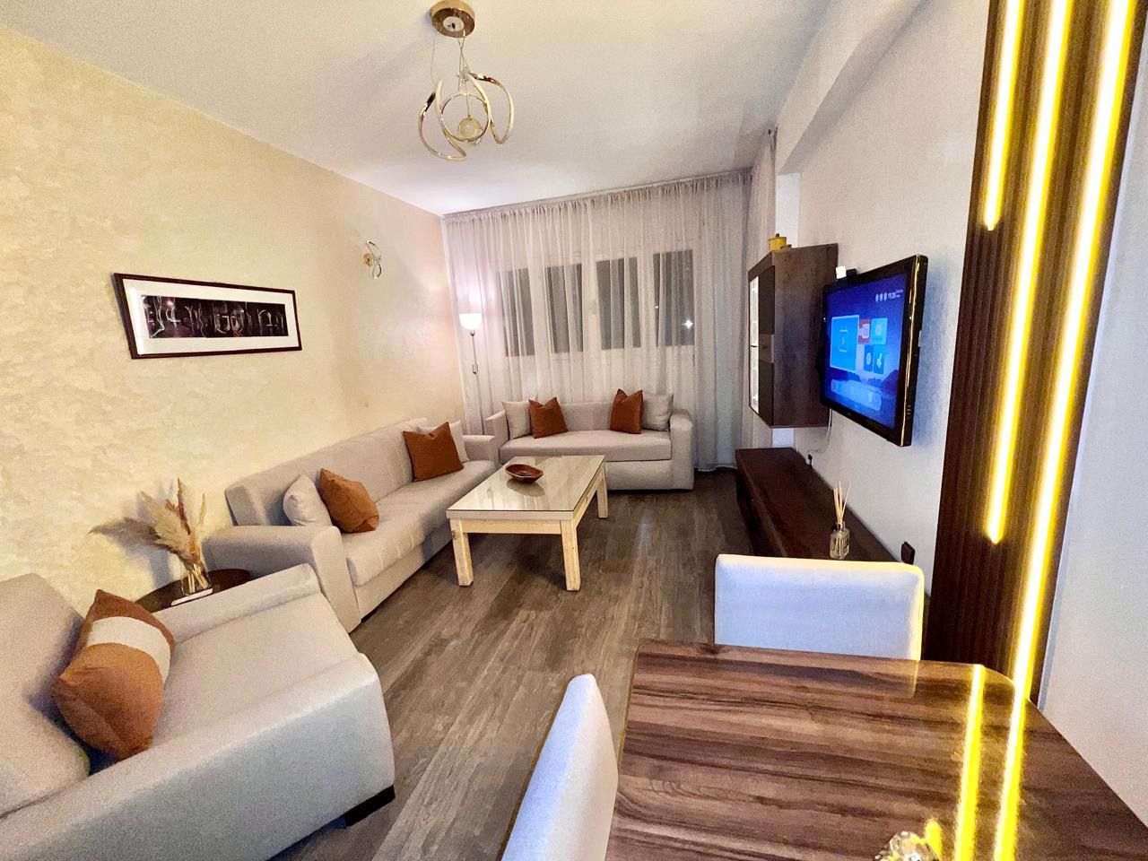 A modern living room with a sofa set, a coffee table, and a TV mounted on the wall.