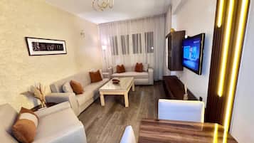 A modern living room with a sofa set, a coffee table, and a TV mounted on the wall.