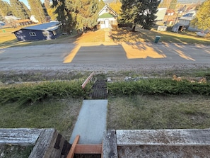 A residential area with a paved road, a small drainage grate, and a wooden fence.