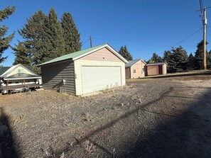 Un quartier résidentiel avec une allée en gravier, un garage et un petit abri de jardin.