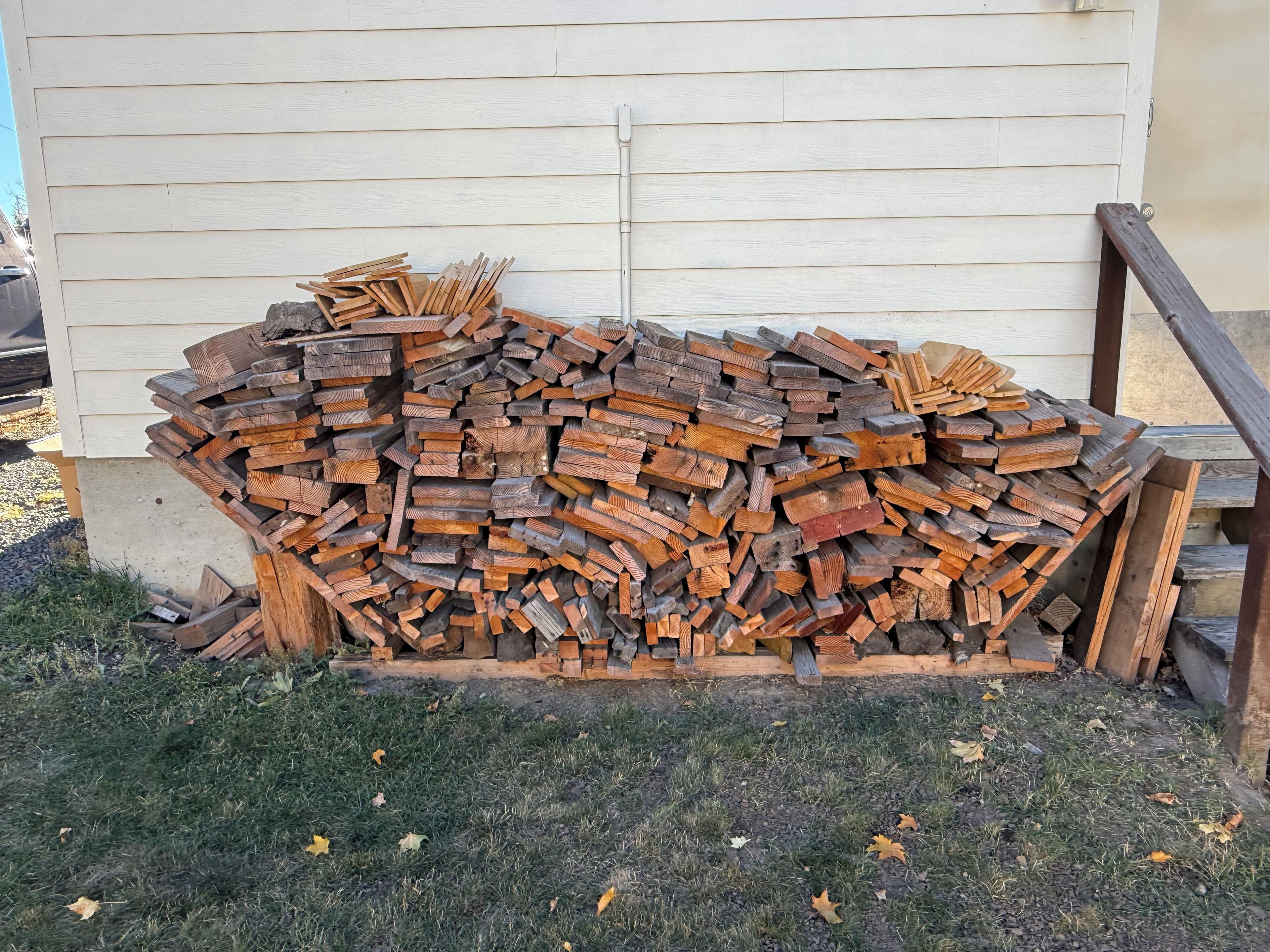 A stack of firewood against a building with horizontal siding.