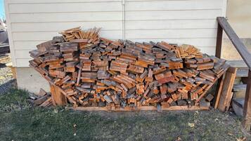 A stack of firewood against a building with horizontal siding.