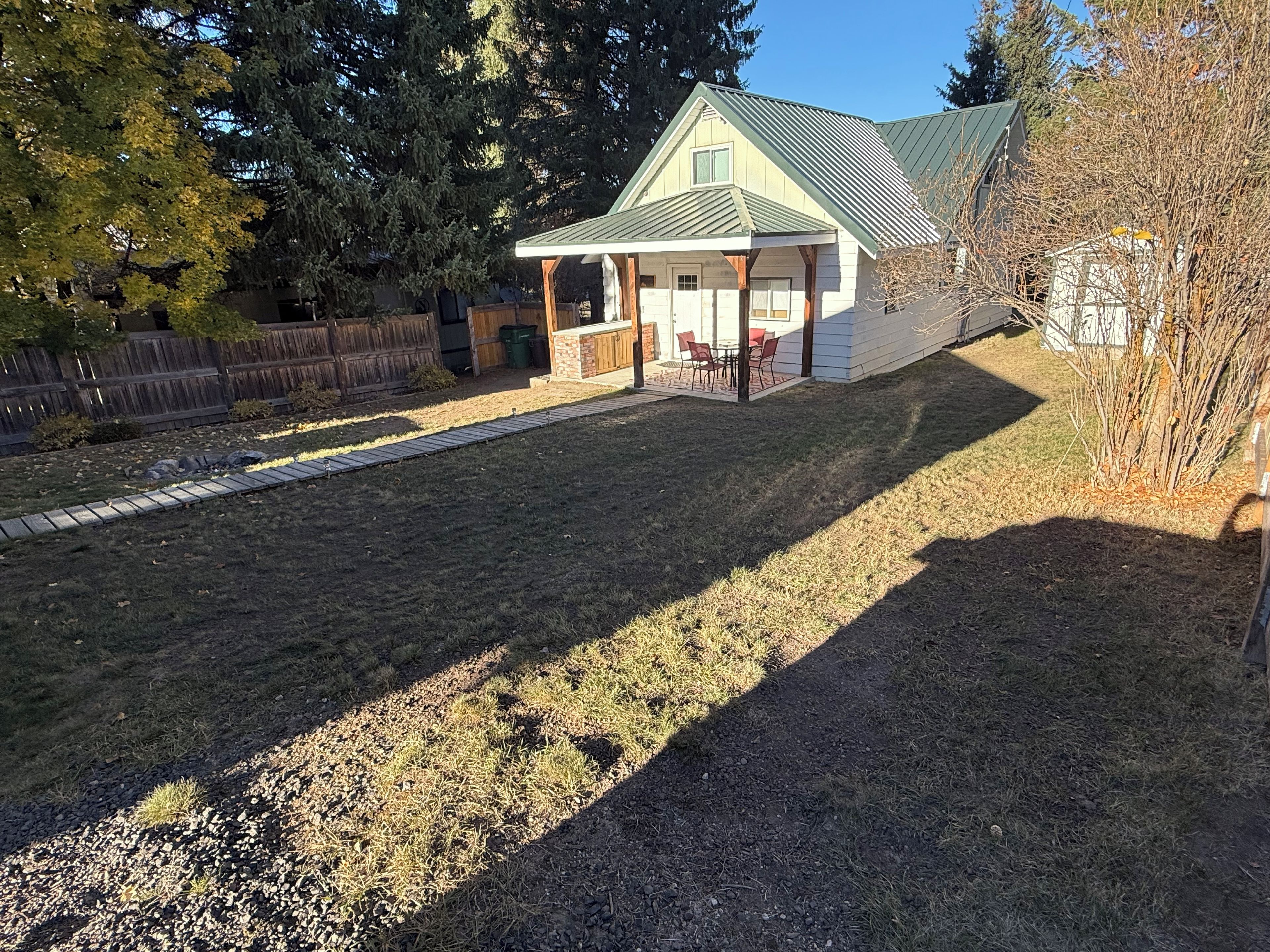 Ein Wohnhaus mit überdachter Terrasse, umzäunter Garten und einem Dachgarten.