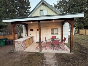 A covered outdoor patio with a brick countertop and red chairs.