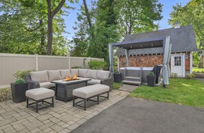 An outdoor patio with a sectional sofa, a fire pit, and a grill area.